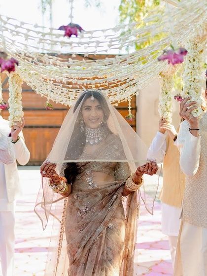 The bride's entrance under a delicate 'phoolon ki chadar'. This moment is always so special, and we ensured the floral canopy was light and elegant to complement her serene look and the overall minimalist decor.