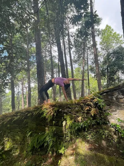 The Wheel Pose, or Chakrasana, is a deep backbend that energizes the whole body. Practicing it on a moss-covered structure in the middle of the forest helps to draw awareness inward, away from the external world.