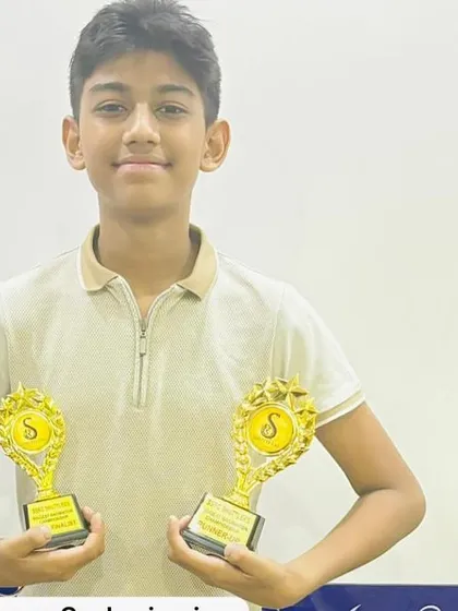 Double the success. A young player from our academy proudly holds up two trophies won at a recent badminton championship.