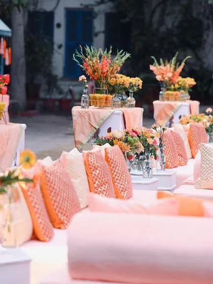 Another angle of the diwan seating, showcasing the layers of cushions and the console tables behind them styled with beautiful gladiolus arrangements.