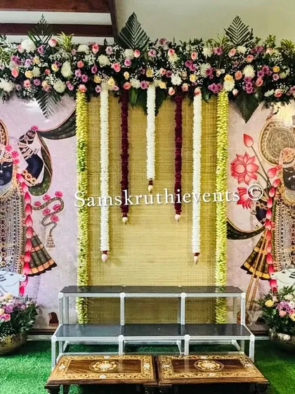 A beautiful pooja setup inspired by Pichwai art. We used traditional paintings of Lord Shrinathji as the centerpiece, framed by banana plants, fresh flowers, and elegant brass pots for a serene and artistic look.