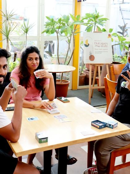 A card game in session on the rooftop terrace. The natural light and green plants create a refreshing environment for a friendly competition.