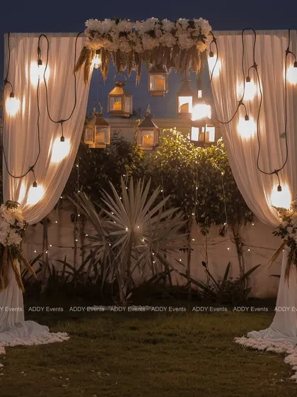 A wider view of the romantic bohemian arch, showcasing its placement on a lush green lawn, making it an ideal focal point for an outdoor evening event.