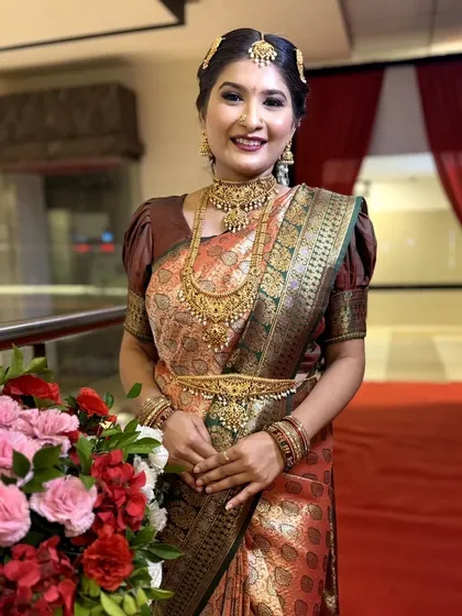 This bride's smile lights up the frame. The makeup is designed to enhance her natural glow, with a focus on well-defined eyes and a warm lip color.