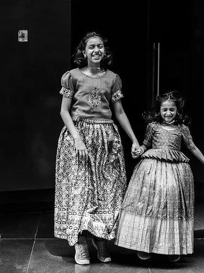 The infectious joy of siblings holding hands at a family event. This candid black and white photo captures the energy and connection between children during a celebration.