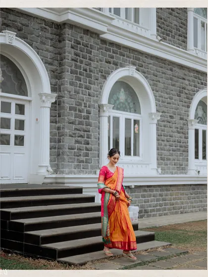 An environmental portrait of the bride descending the steps of a stone building. This wide shot places her in a grand architectural setting, emphasizing the timeless elegance of her traditional attire.