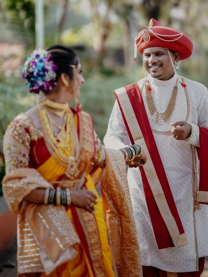 We love capturing the playful interactions between our couples. Here, the groom gently holds his bride's hand, sharing a laugh during their Maharashtrian wedding photoshoot.