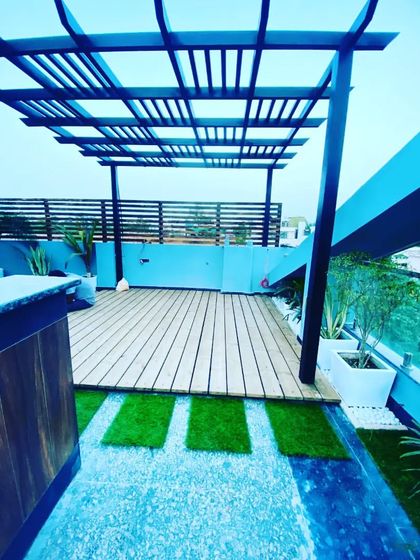 A matt black pergola with a thermopine wood deck in Vikaspuri. This design combines modern metalwork with the warmth of natural wood.