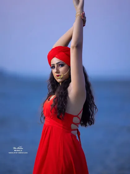 A dynamic pose from the desert-themed shoot, with the model in a striking red dress and turban against the open landscape.