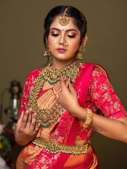 A portrait of elegance. This model showcases a full bridal look with a heavy temple jewellery set, featuring a wide choker and a long haram with green stone accents.