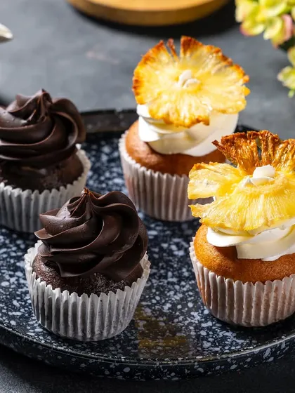 A close-up of chocolate and pineapple cupcakes for Ferns N Petals Luxe, showcasing two different flavors in one shot.
