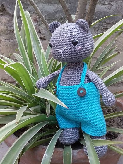 Coal the Kitten looking out from behind a plant. I used a lovely grey yarn for his body and added simple embroidered details for his face.