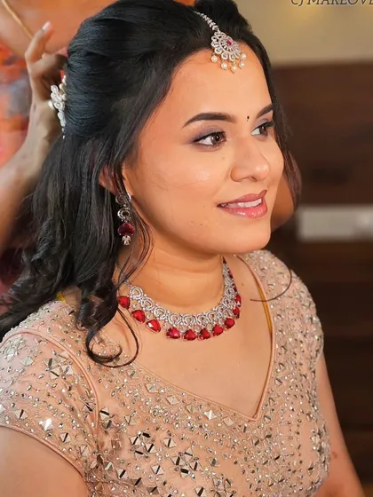 A close-up of the reception look, showing the soft curls and the beautiful ruby and diamond jewelry. The makeup is subtle yet glamorous.