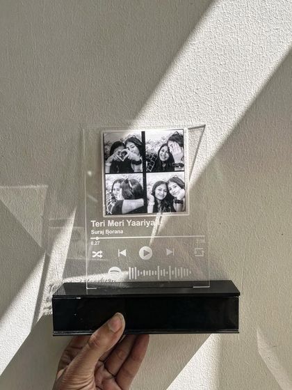 A Spotify polaroid plaque with a standee. This is a great desk accessory that combines four of your favorite photos with the scannable code for your friendship anthem.