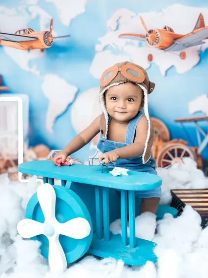Flying high for his first birthday! The airplane prop and world map backdrop set the scene for a global adventure.