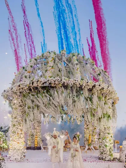 A grand finale to the vows. We coordinated this stunning display of floral structures and colored smoke to create a truly unforgettable exit from the mandap for Aditya and Drishti.