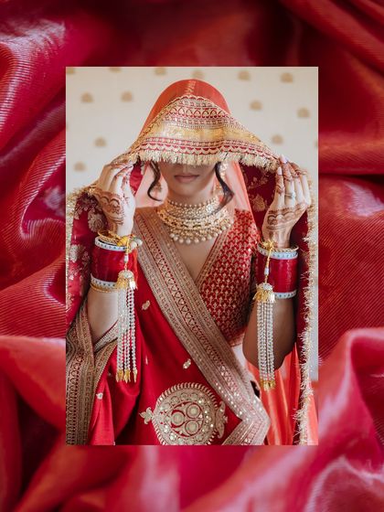 An artistic edit of a bride adjusting her veil, framed by a rich, textured red background.