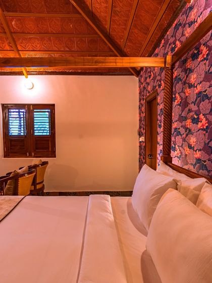 This view showcases the room's beautiful wooden ceiling and slatted window, which add to the rustic charm. The design prioritizes natural materials and traditional craftsmanship to create a serene guest experience.