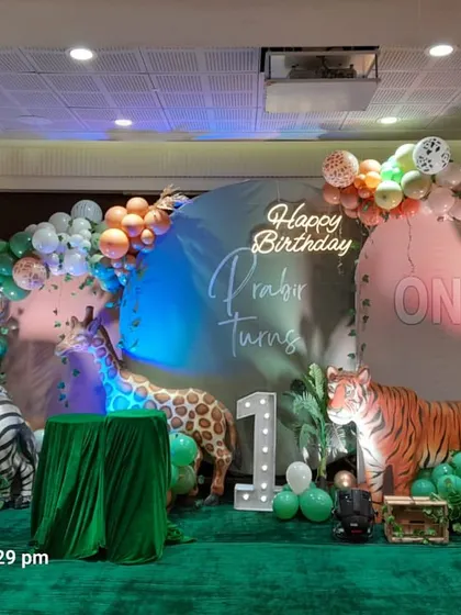 A full view of the stage for a "Wild One" birthday, showcasing the arrangement of animal props, balloon garlands, and the light-up number '1' that marks the special occasion.