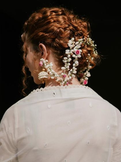 A view of the bride's hairstyle for the Haldi. Her hair is beautifully braided and adorned with delicate baby's breath and pink flowers, tying the whole look together.
