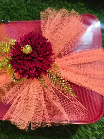 A simple yet elegant wrapping for a small gift box, using orange net and a beautiful artificial flower.