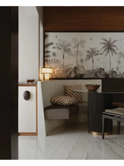 A closer look at the arc-shaped dining nook, designed to utilize an odd corner of the room efficiently. The cement-finished bench seating and tropical mural create a picturesque and intimate setting for meals, proving that small spaces can be highly functional.