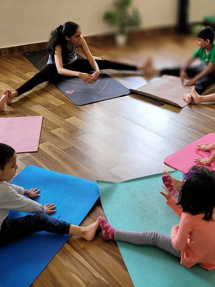 A circle of young yogis stretching together. Group activities like this help build a sense of community and shared experience in the class, making everyone feel included and supported.