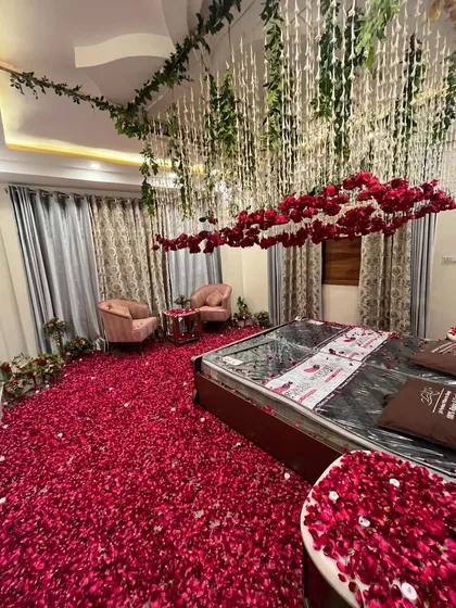 A truly romantic 'welcome bride' room decoration. The entire floor is covered in a thick carpet of red rose petals, with a stunning floral canopy of red roses and white tuberoses hanging from the ceiling over the bed.