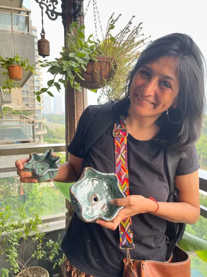 A student proudly holding her two unique, flower-like bowls, fresh from the kiln with a beautiful green glaze.
