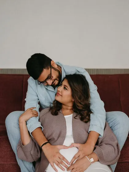 A heartwarming photo celebrating their growing family. Her makeup is soft and glowing, perfect for capturing this precious memory.