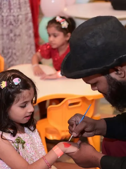 A little girl getting her hand painted. We ensure all materials used are child-safe and non-toxic.