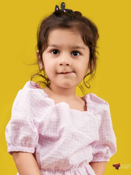 A delightful and natural kid's portrait. The bright yellow background adds a playful energy, while the soft studio lighting creates a warm and gentle look, capturing the child's sweet expression.