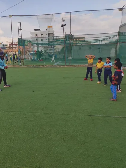 A coach demonstrating a batting technique to a group of very young players. We make learning accessible and fun for our U-10 batches.