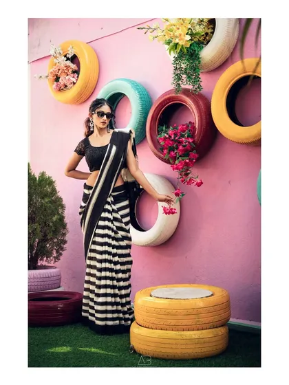 A great commercial shoot is about creating a visual that pops. The contrast between the classic black and white striped saree and the vibrant, quirky background of colorful tires makes for a memorable and energetic fashion photograph.