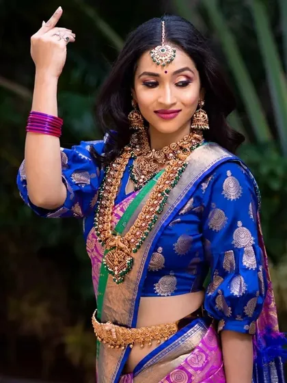 A vibrant look with a blue and pink saree. The makeup is bright and festive.