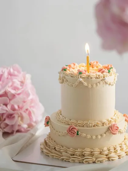 Tiered cakes are perfect for making a statement at big celebrations. This alluring two-tier vintage cake features delicate buttercream roses and classic piping. The bottom tier was a vanilla cake with our homemade strawberry compote, and the top was a delicious butterscotch flavor.