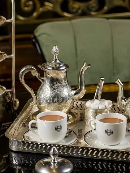 A classic high tea setup at United Coffee House, featuring an ornate silver tea set. The image captures the luxurious and traditional ambiance of the location.