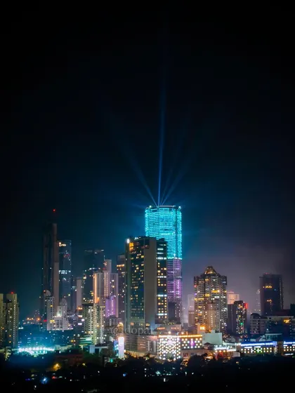 The Palais Royale skyscraper in Mumbai is lit up with blue lights and powerful spotlights, creating a beacon in the night sky.