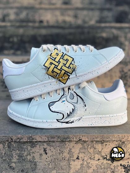 A unique design for a client who wanted to represent his spirit animal and beliefs. We painted a golden Karma symbol on one Adidas shoe and a white wolf on the other, both accented with paint splatters.