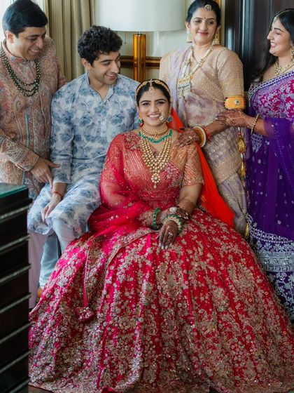 A final family portrait, with everyone looking lovingly at the bride. The color palette of red, purple, and pastels creates a rich and visually pleasing photograph that the family will treasure.