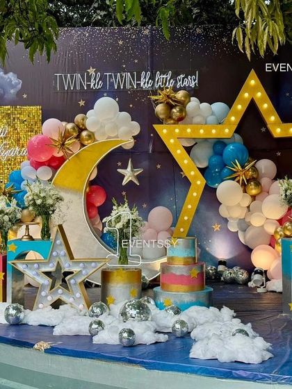 A full view of the "Twinkle Twinkle" stage setup by a pool, with the decor reflecting beautifully on the water. The use of pink and blue balloons makes it perfect for boy-girl twins.