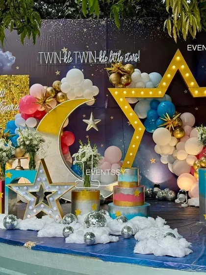 A full view of the "Twinkle Twinkle" stage setup by a pool, with the decor reflecting beautifully on the water. The use of pink and blue balloons makes it perfect for boy-girl twins.