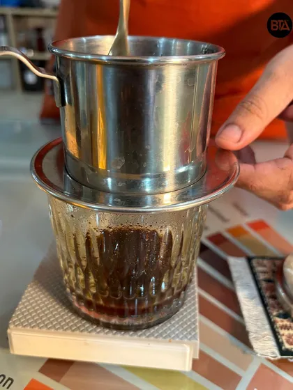 A close-up of a Vietnamese Phin filter. This traditional drip coffee maker is essential for brewing authentic, bold Vietnamese coffee.
