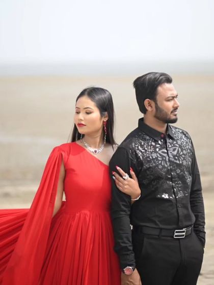 A chic and modern pose on the beach. The one-shoulder design of the red gown is highlighted here, offering a stylish look for the contemporary couple.