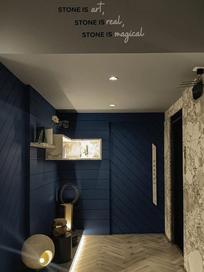 The entrance corridor at Paarkhi, where a deep blue grooved wall creates a dramatic and textural backdrop. A custom-lit marble shelf and floor-level lighting guide the eye through the space, building anticipation.