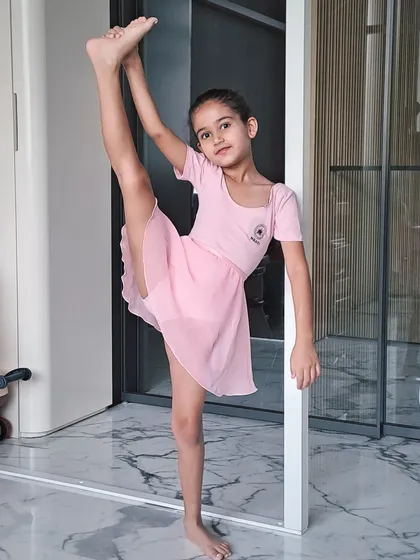 This student demonstrates a standing split, a testament to her hard work and the focus on flexibility in our training.