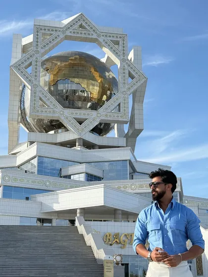 The sky blue shirt stands out against the stunning modern architecture, reinforcing its contemporary appeal.