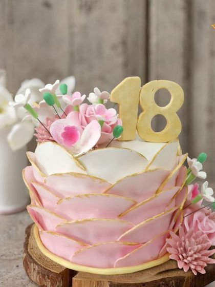 A stunning cake to celebrate a milestone 18th birthday for Ishita in Rajouri Garden. The cake is wrapped in delicate, gold-edged petals and topped with beautiful pink sugar flowers.