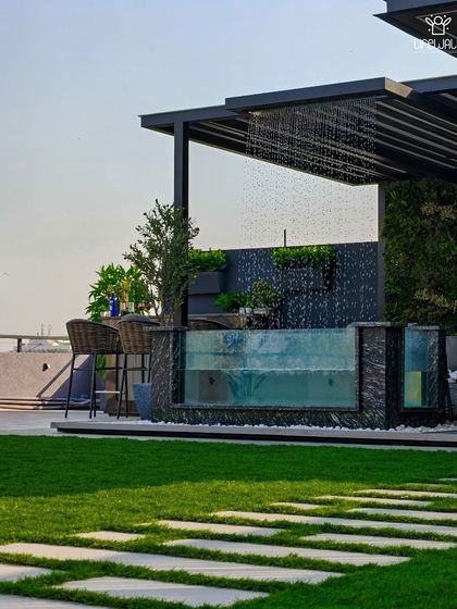 A daytime view of a stunning glass-walled pool with an integrated rain shower feature, set against a backdrop of a vertical garden. This is luxury and relaxation combined.