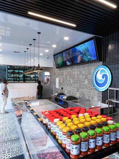 This angle shows the integration of digital screens and brand logos within the fish and meat section. The patterned tile floor adds a decorative touch while being practical for a high-use area.